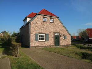 a brick house with a red roof and a driveway at Comfy farmhouse villa in Limburg in Roggel