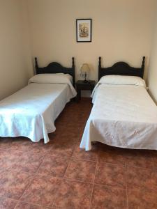 Habitación con 2 camas y suelo de baldosa. en La Plaza, en Zuheros