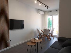 un salon avec une table et une télévision au mur dans l'établissement Apartamento vacacional Cuarteles, à Malaga