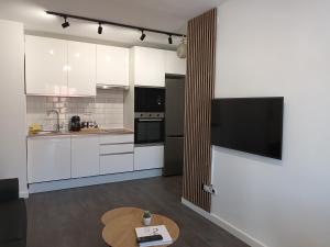 une cuisine avec des armoires blanches et une table en bois dans l'établissement Apartamento vacacional Cuarteles, à Malaga