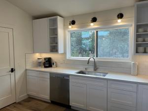 a kitchen with white cabinets and a sink and a window at Thunder Hollow in Ruidoso +42 photos
