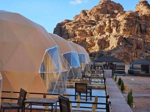 a row of tables and chairs in front of a mountain at Sunrise Luxury Camp in Wadi Rum