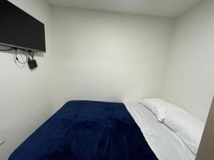Ce lit se trouve dans une chambre blanche dotée d'une couverture bleue. dans l'établissement Apartaloft en el centro 205, à Pereira