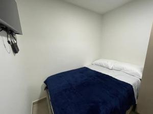 Cette chambre blanche dispose d'un lit avec une couverture bleue. dans l'établissement Apartaloft en el centro 205, à Pereira