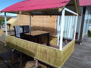 cenador con mesa y sillas en la terraza en Coila Titicaca lodge, en Puno