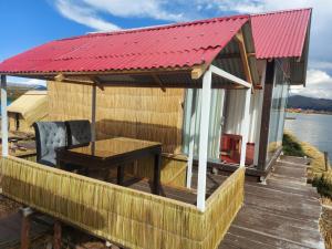 普諾的住宿－Coila Titicaca lodge，一座红色屋顶的房子,甲板上设有一张桌子