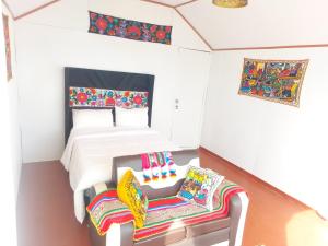 Coila Titicaca lodge في بونو: غرفة نوم بسرير وكرسيين