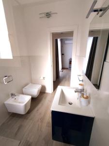 La salle de bains blanche est pourvue d'un lavabo et de toilettes. dans l'établissement L'Angolo di Mimma, à Porto Cesareo