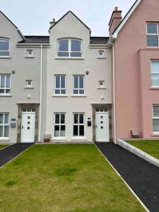 a large house with white doors and a grass yard at Coastal Haven 5 Bed Gem in Portrush Center in Portrush