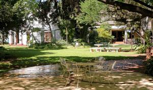 two chairs and a table under a tree in a park at Pumulani Lodge in Pretoria