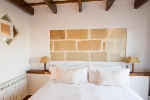 1 dormitorio con cama blanca y pared de ladrillo en Llucmaçanes Gran Agroturismo, en Mahón