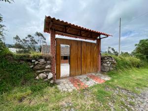una pequeña casa con una puerta de madera en un campo en Casita Hierbabuena en Ibarra