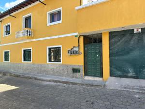 un edificio amarillo con una puerta verde de garaje en una calle en Departamento Independiente completo, Centro Histórico Quito en Quito