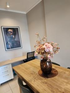 a vase of flowers sitting on a wooden table at 10th floor, Unit 1008, in The Capital Trilogy, overlooking Sun Time Square in Pretoria