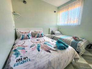 1 Schlafzimmer mit 2 Betten und Meerjungfrauenkissen in der Unterkunft Appartement cosy tout équipé centre-ville, Tlemcen in Tlemcen