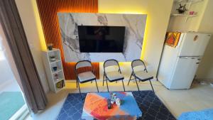 Elle comprend un salon avec des chaises, une télévision et un réfrigérateur. dans l'établissement Relaxing Studio-Malibu El Sokhna Resort, à Ain Sokhna