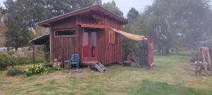um pequeno barracão de madeira com uma cadeira num quintal em Chacrita Aguaribay em Villa Argentina