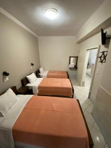 a hotel room with three beds and a television at Paradosi Rooms in Igoumenitsa