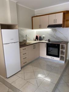 Il comprend une cuisine équipée d'appareils électroménagers blancs et d'un réfrigérateur blanc. dans l'établissement Paradosi Rooms, à Igoumenítsa
