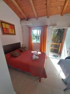 Un dormitorio con una cama roja con dos animales de peluche. en Complejo Cantonavi en Mina Clavero