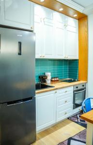 a kitchen with white cabinets and a stainless steel refrigerator at Albanian Dream Escape Apartment in Golem