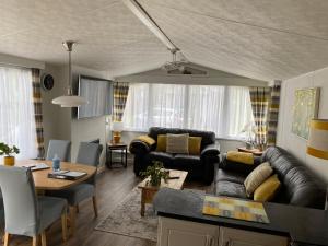 ein Wohnzimmer mit einem Sofa und einem Tisch in der Unterkunft All Weather Hot Tub & Cosy Cabin in Northumberland in Morpeth
