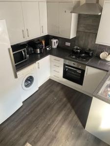 a kitchen with white cabinets and a stove top oven at White and Sandstone Astley Bridg in Bolton