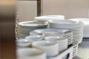 a stack of white plates and bowls on a shelf at Vogar Travel Service in Myvatn