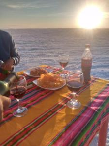 a table with glasses of wine and food on the beach at salt beds of salt hostal in Uyuni