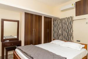 Schlafzimmer mit einem Bett und einem Spiegel in der Unterkunft Live Inn RMS in Tiruchchirāppalli