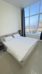 a white bed in a room with a large window at P3) Fantastic Seaview Room with shared bath inside 3bedroom apartment in Ajman 