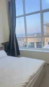 una cama en una habitación con una ventana grande en P3) Fantastic Seaview Room with shared bath inside 3bedroom apartment, en Ajman