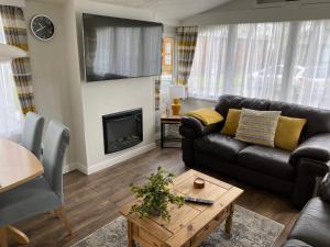 ein Wohnzimmer mit einem Sofa und einem Kamin in der Unterkunft All Weather Hot Tub & Cosy Cabin in Northumberland in Morpeth