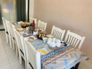una mesa con comida y sillas blancas en Sakhohostel, en Karategin