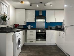 cocina con armarios blancos, lavadora y secadora en Pointcastle, en West Thurrock