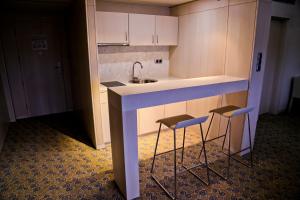 a small kitchen with a sink and two stools at Hotel Svilena in Svilengrad