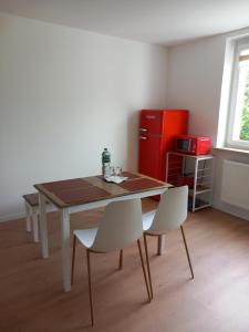 kuchnia ze stołem, 2 krzesłami i czerwoną lodówką w obiekcie City Apartment Duisburg 2#Netflix &Wlan &Kingsize Bett &Central w mieście Duisburg