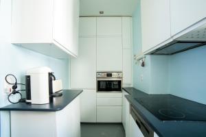 eine Küche mit weißen Schränken und einer schwarzen Arbeitsplatte in der Unterkunft Cozy one bedroom Appartement 16 ème Paris - Trocadéro in Paris