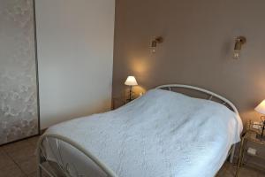 a white bed in a bedroom with two lamps at Lovely house with garden close to the beach in Sainte-Marie-de-Ré
