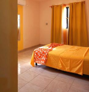 Un dormitorio con una cama con una manta amarilla. en Casa Aeropuerto Mérida, Yucatán, en Mérida
