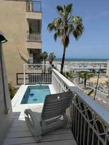 a balcony with a chair and a swimming pool at Sweet li in Ashqelon