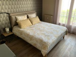 - une chambre avec un lit et des oreillers dans l'établissement Au cœur de Lisieux 83 m2 et vue sur la Basilique, à Lisieux