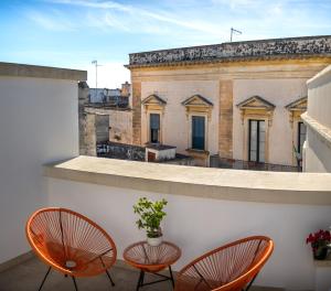 two chairs and a vase on a balcony with a building at La Terrazza Nel Borgo B&B in Copertino