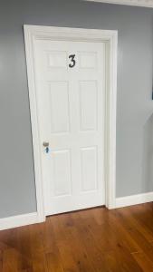 une porte blanche avec le numéro trois sur elle dans l'établissement Don cozy, à Saint Albans