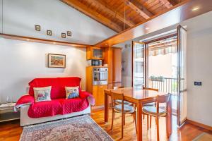 ein Wohnzimmer mit einem roten Sofa und einem Tisch in der Unterkunft Valtenesi Appartment - Residence Pool - by HOST4U in Manerba del Garda