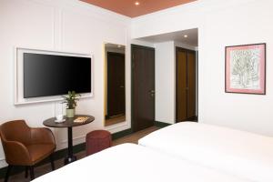 a bedroom with a bed and a table and a tv at The Welbeck Hotel by IHG in London +90 photos