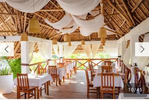 a restaurant with white tables and chairs and ceilings at Ayras Hotel Zanzibar in Paje