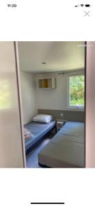 2 camas en una habitación pequeña con ventana en Les Catalpas *** charmant mobilhome à louer, en Saint-Georges-de-Didonne