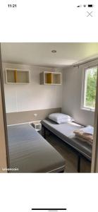 een kamer met 2 bedden en een raam bij Les Catalpas *** charmant mobilhome à louer in Saint-Georges-de-Didonne