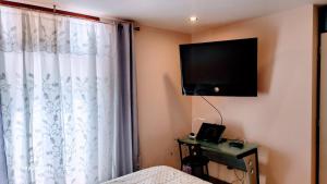 una camera da letto con un letto e una televisione a parete di Mini Departamento Acogedor a La Molina